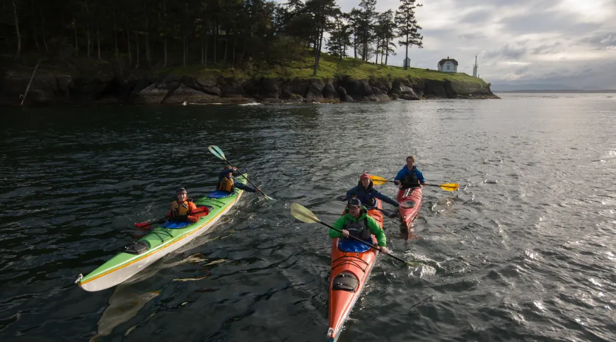 Three kayakers in the Salish Sea, on a tour with San Juan Island Outfitters